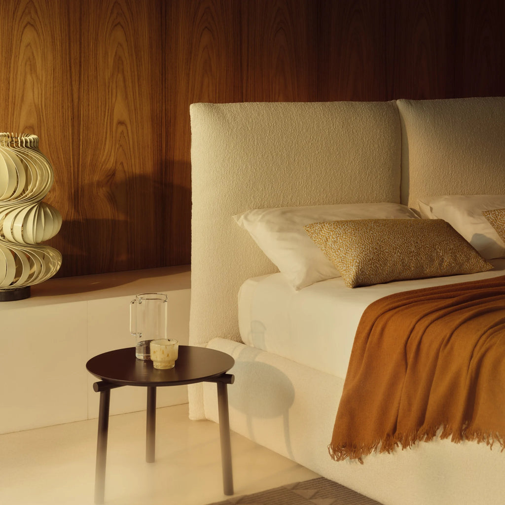 Bedroom with a white boucle bed, black side table, and decorative items from Bolzan at Milola