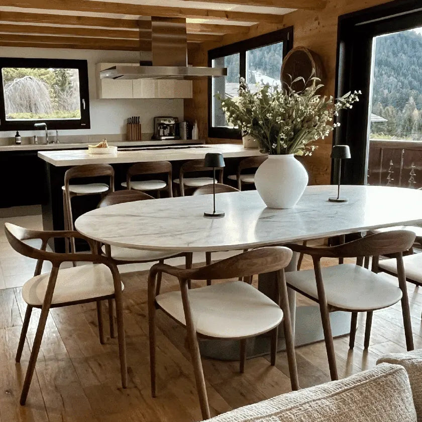 Dining area with marble table and wooden chairs in a modern kitchen setting.